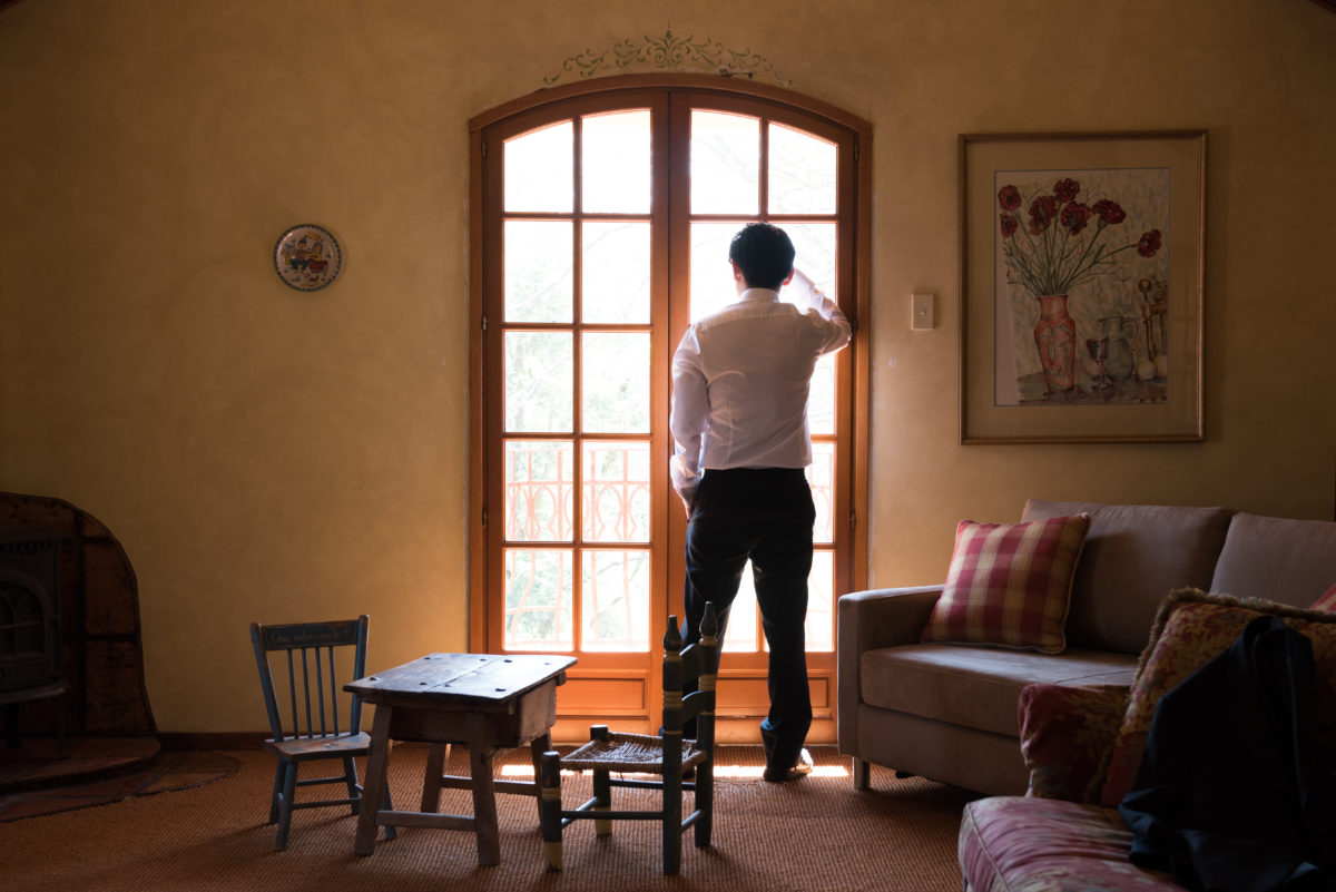 Groom leaning against window looking out