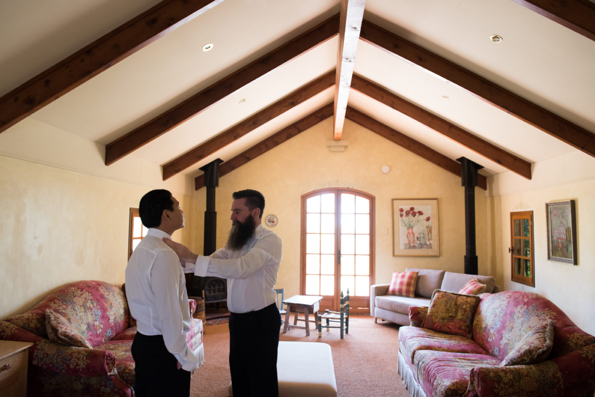 Groom having his tie adjusted by groomsman
