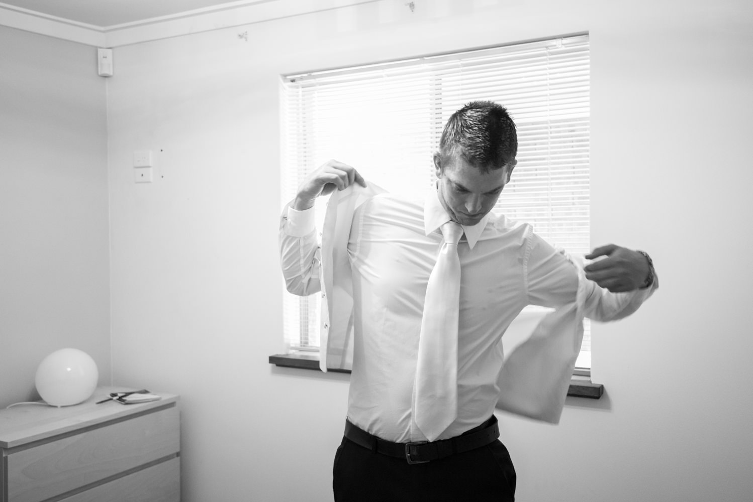 Groom putting vest on