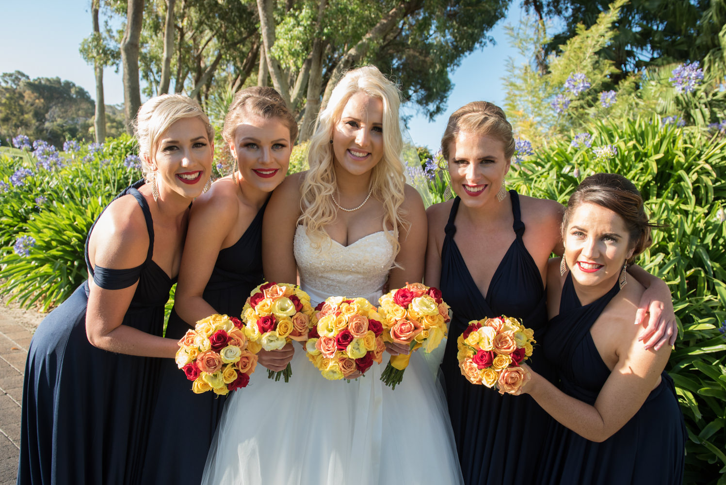 Bride with her bridesmaids, yellow and red bouquets