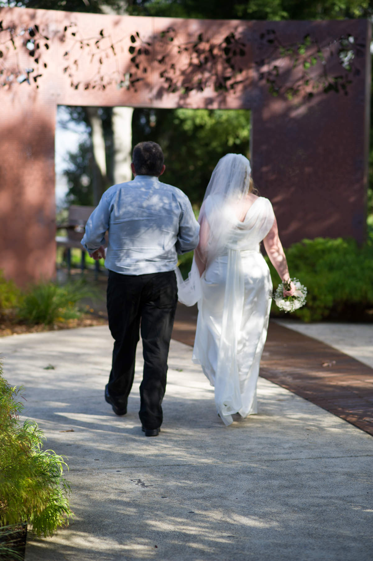 Bride and groom walking under metal sculpture in King's Park, Perth