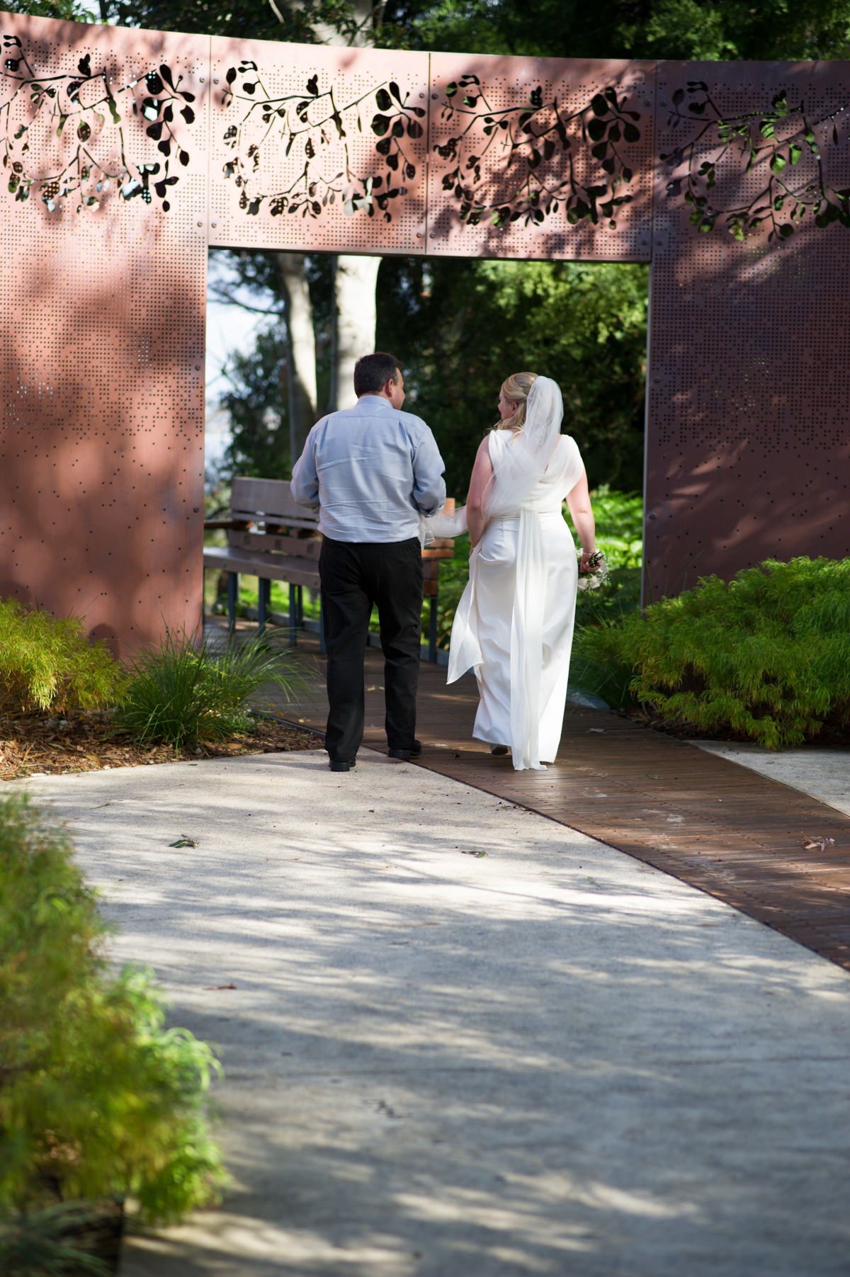 Bride and groom walking under metal sculpture in King's Park, Perth