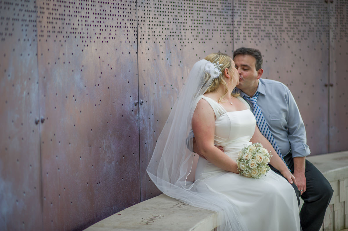 Bride and groom kissing next to metal wall at Marlee pavilion