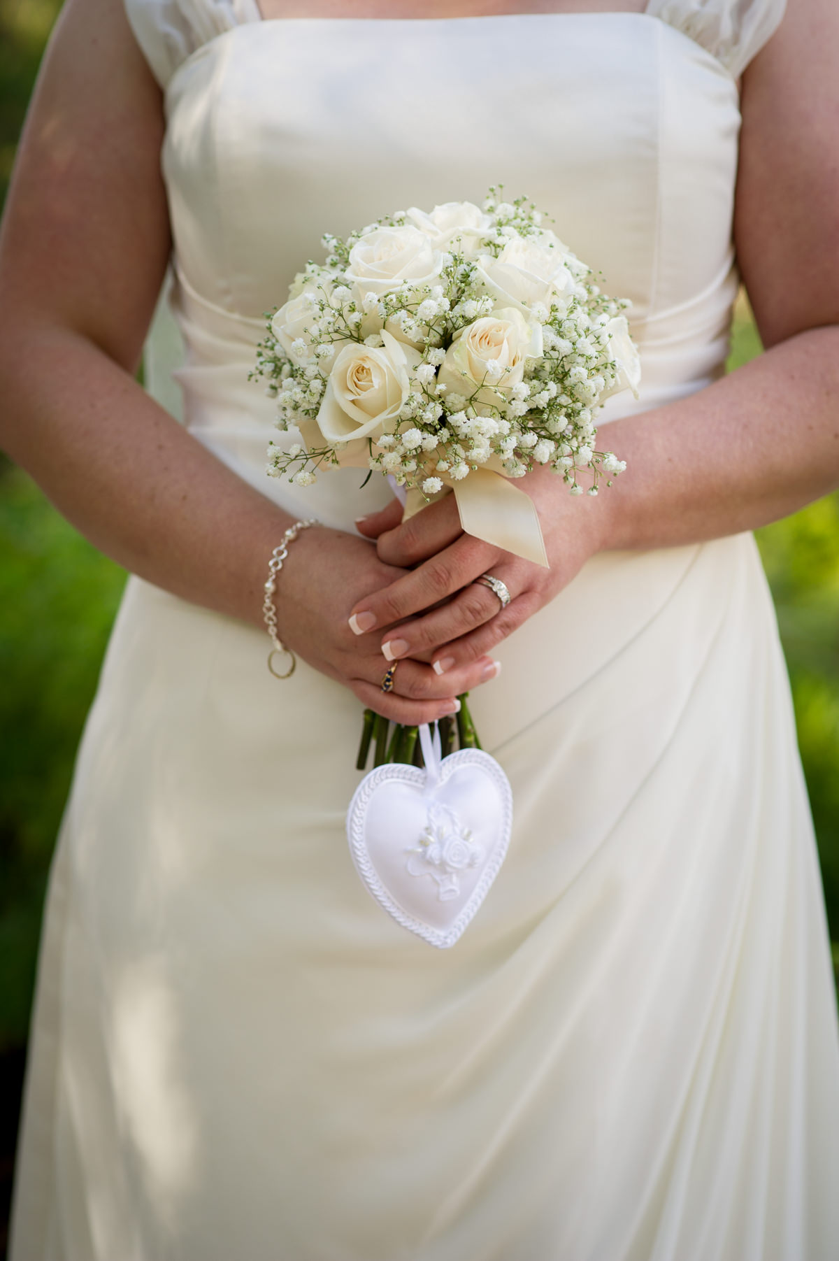 Close up of bride holding bouquet and ring cushion