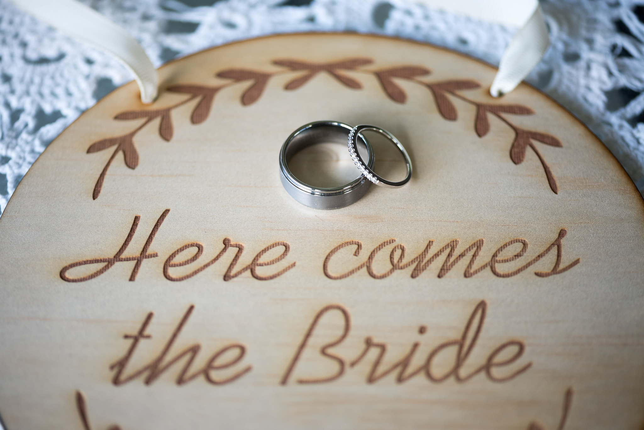 wedding rings on a wood sign that says 'here comes the bride'
