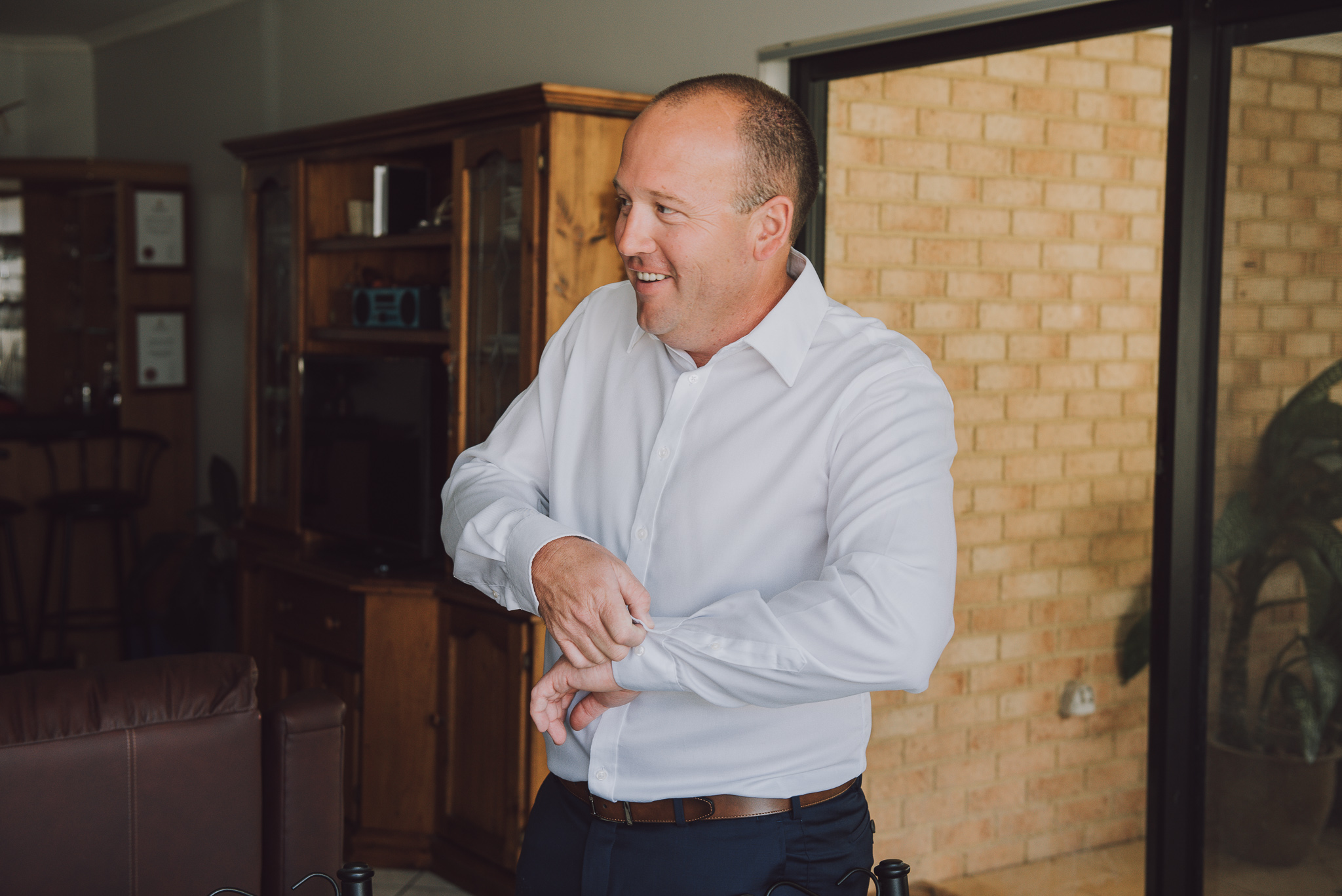 groom laughing while trying to do his cufflink up