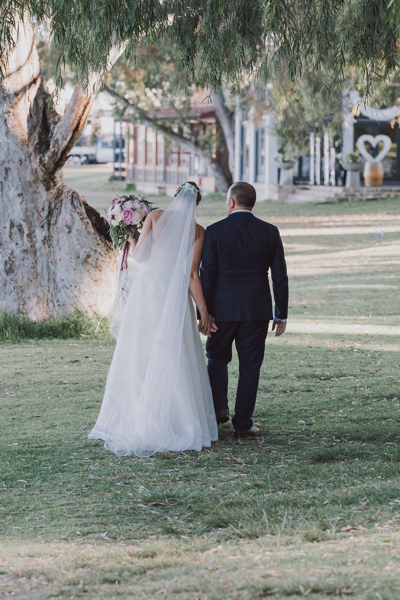Bride and groom holding hands walking away from the camera