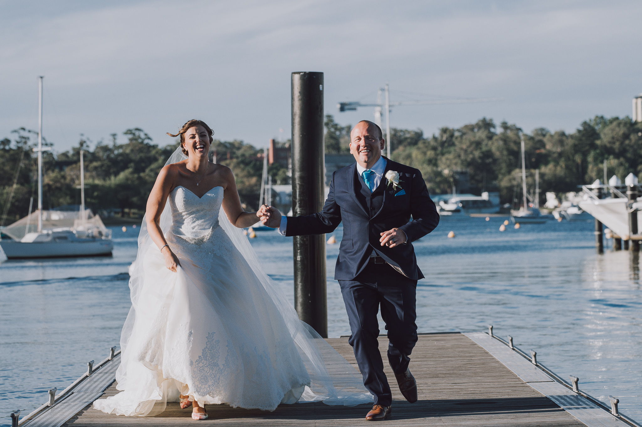bride and groom running on Matilda Bay jetty laughing