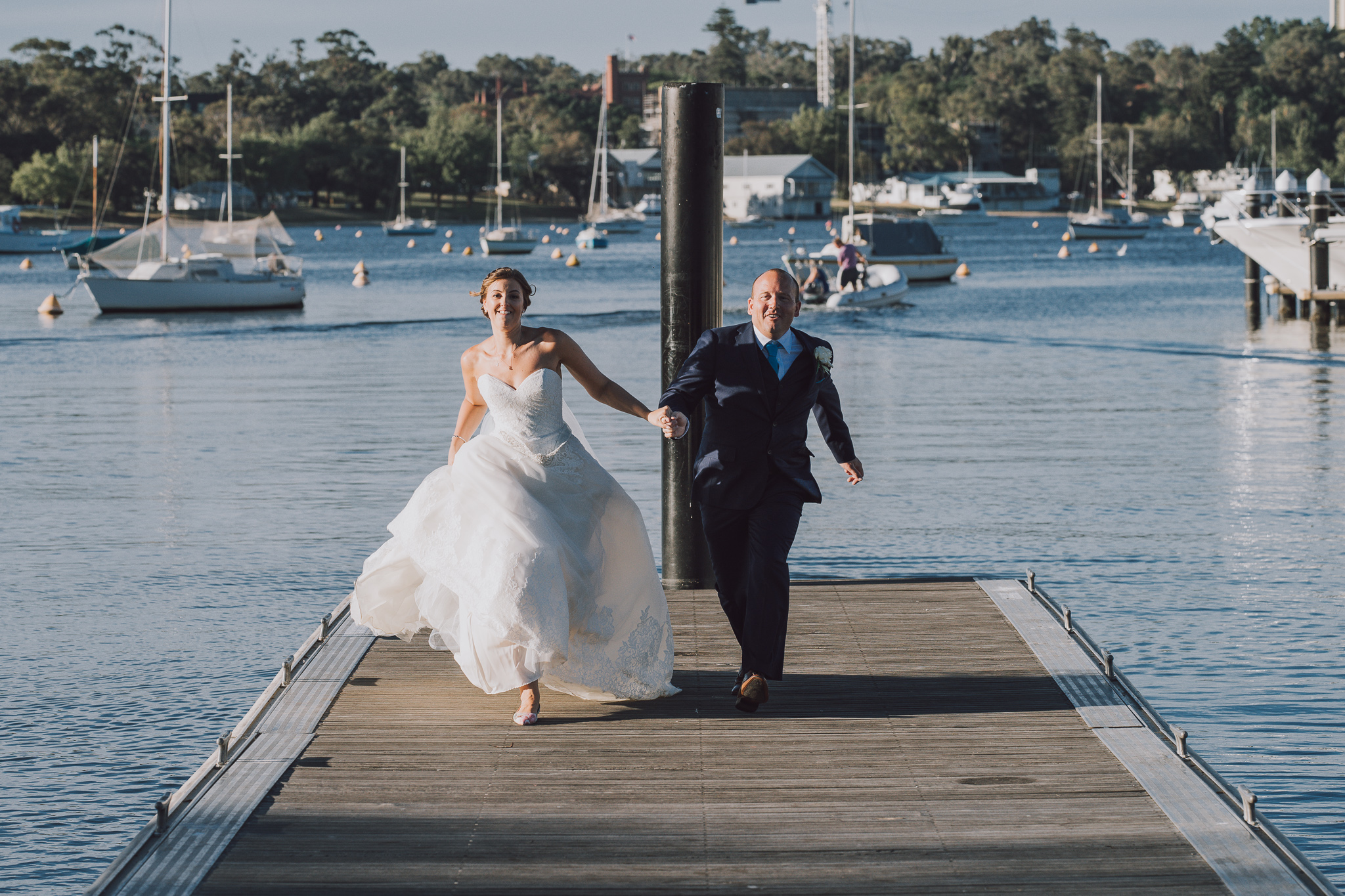 bride and groom running along Matilda Bay restaurant jetty