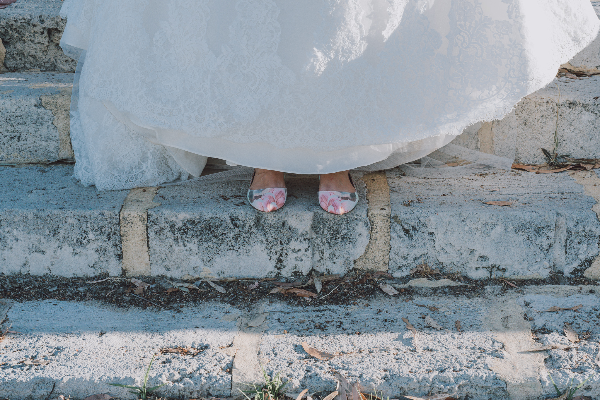 bride's colourful shoes peeping out from beneath her wedding dress