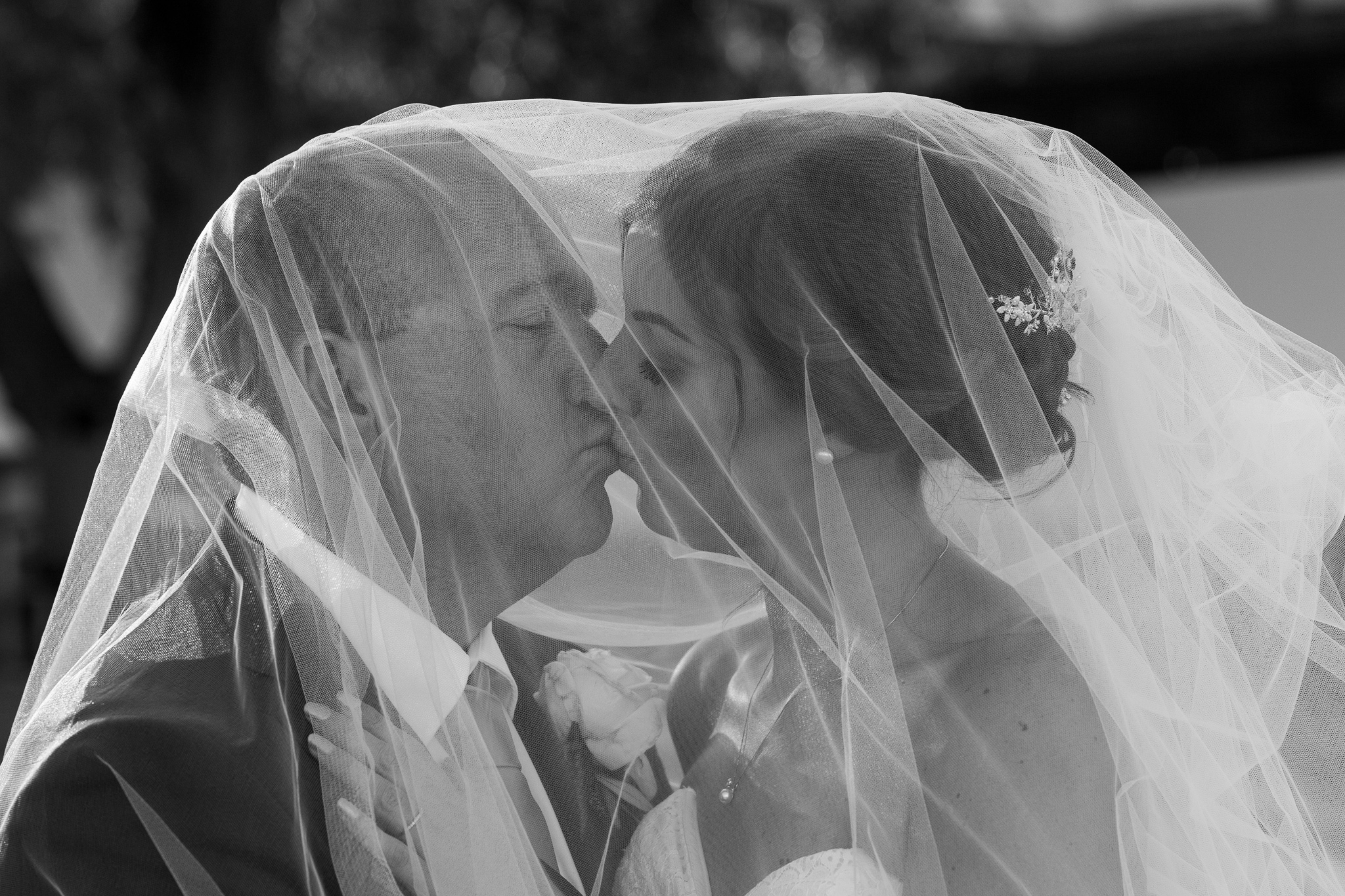 bride and groom kissing underneath her veil