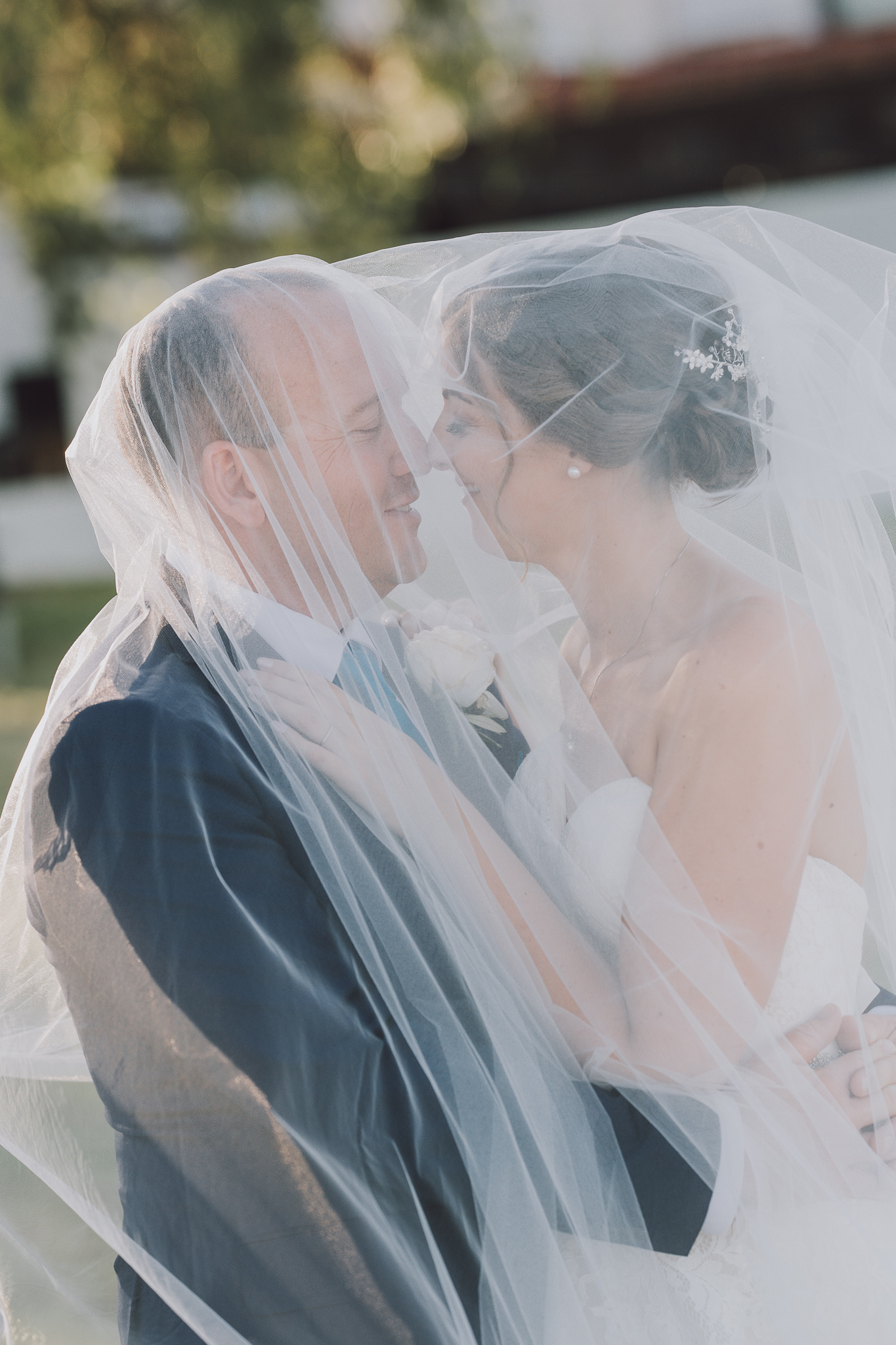 bride and groom cuddling underneath her veil