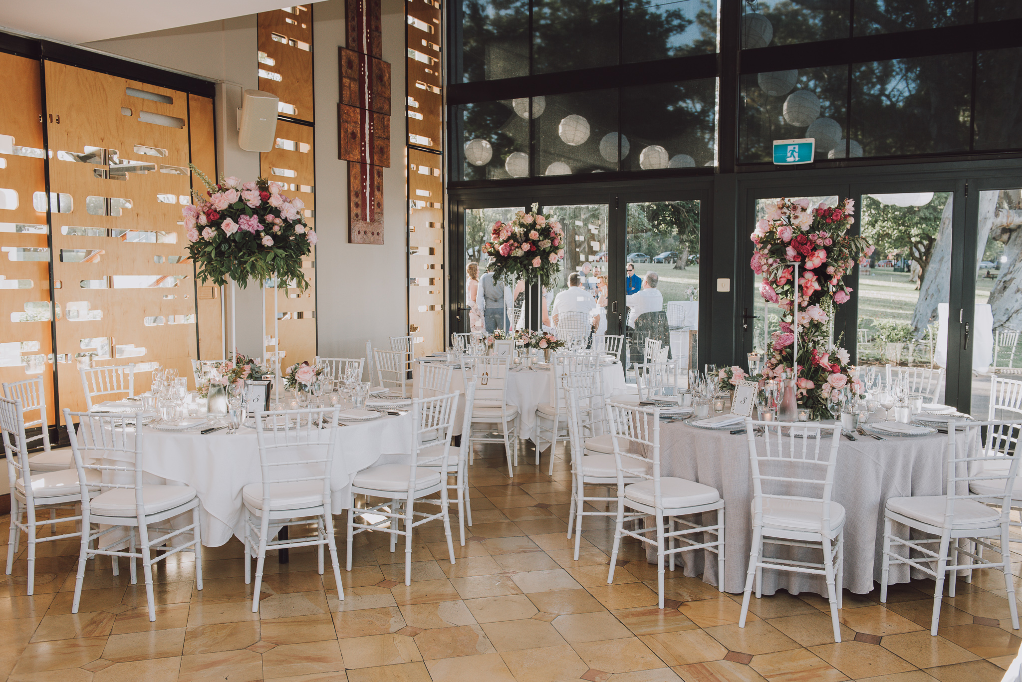 white tiffany chairs and tall floral arrangements on wedding tables at Matilda Bay restaurant