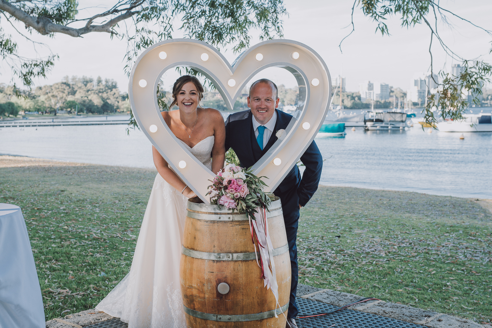 bride and groom peeping through light up love heart at Matilda Bay restaurant