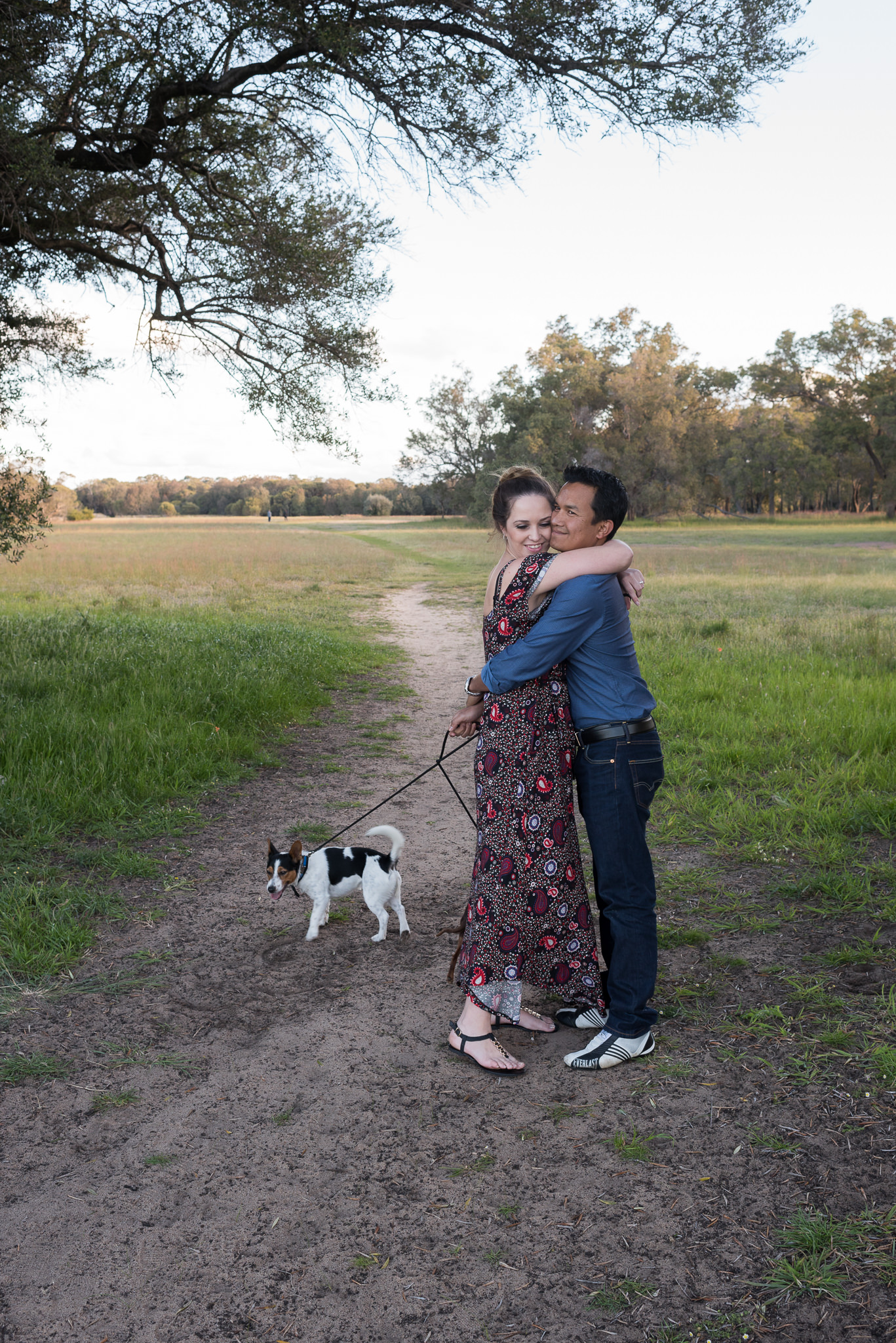 couple has a quick hug as they walk their dog