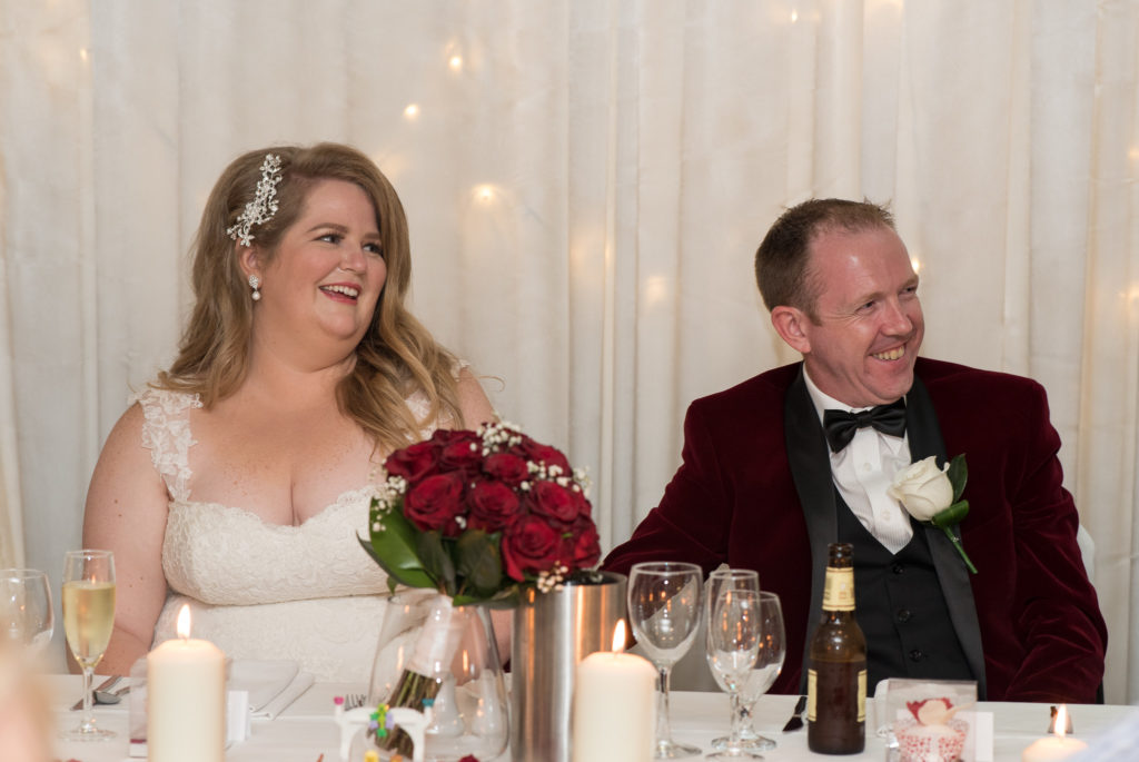 bride and groom smiling during wedding reception speeches