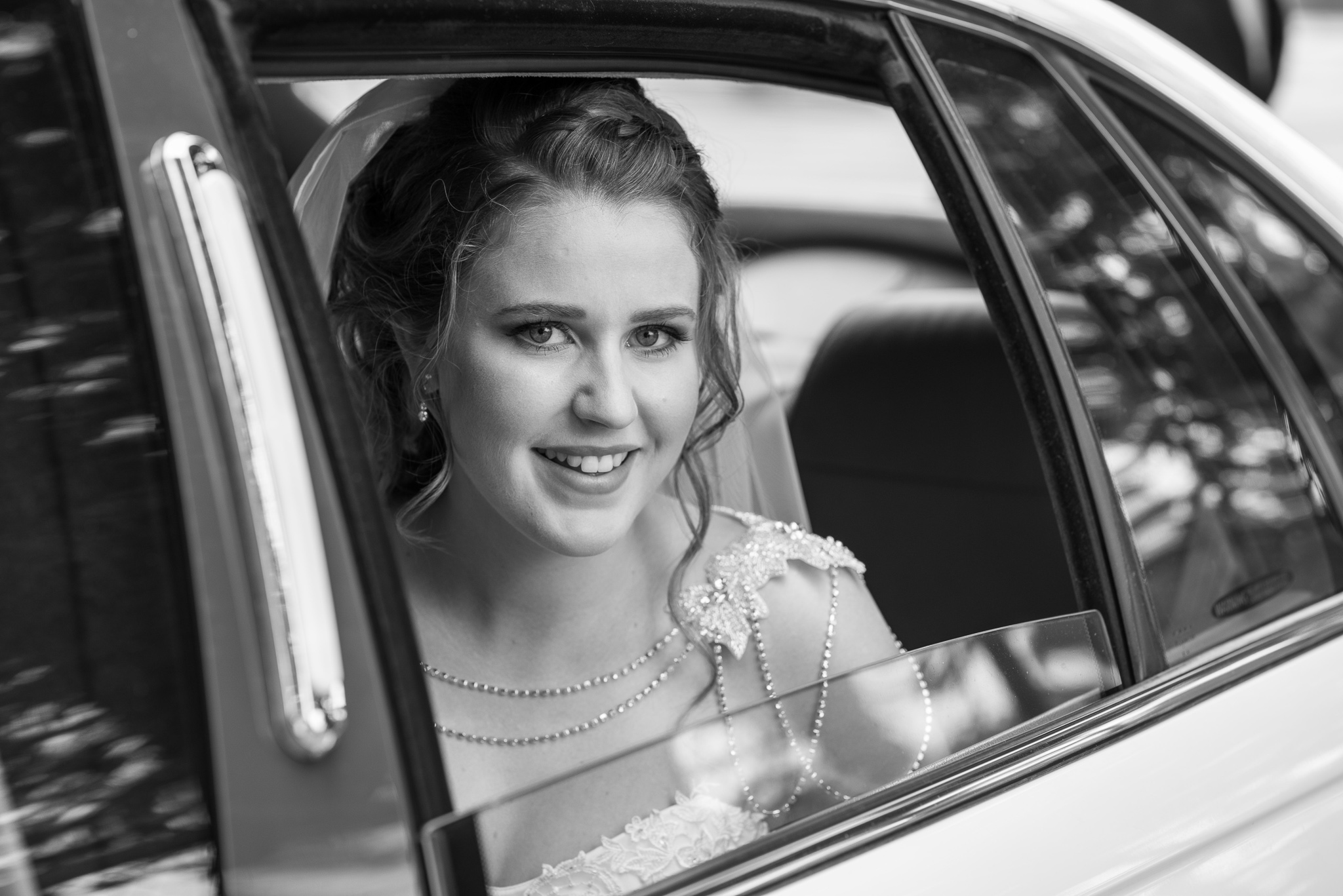 pretty bride looking out of wedding car window in black and white