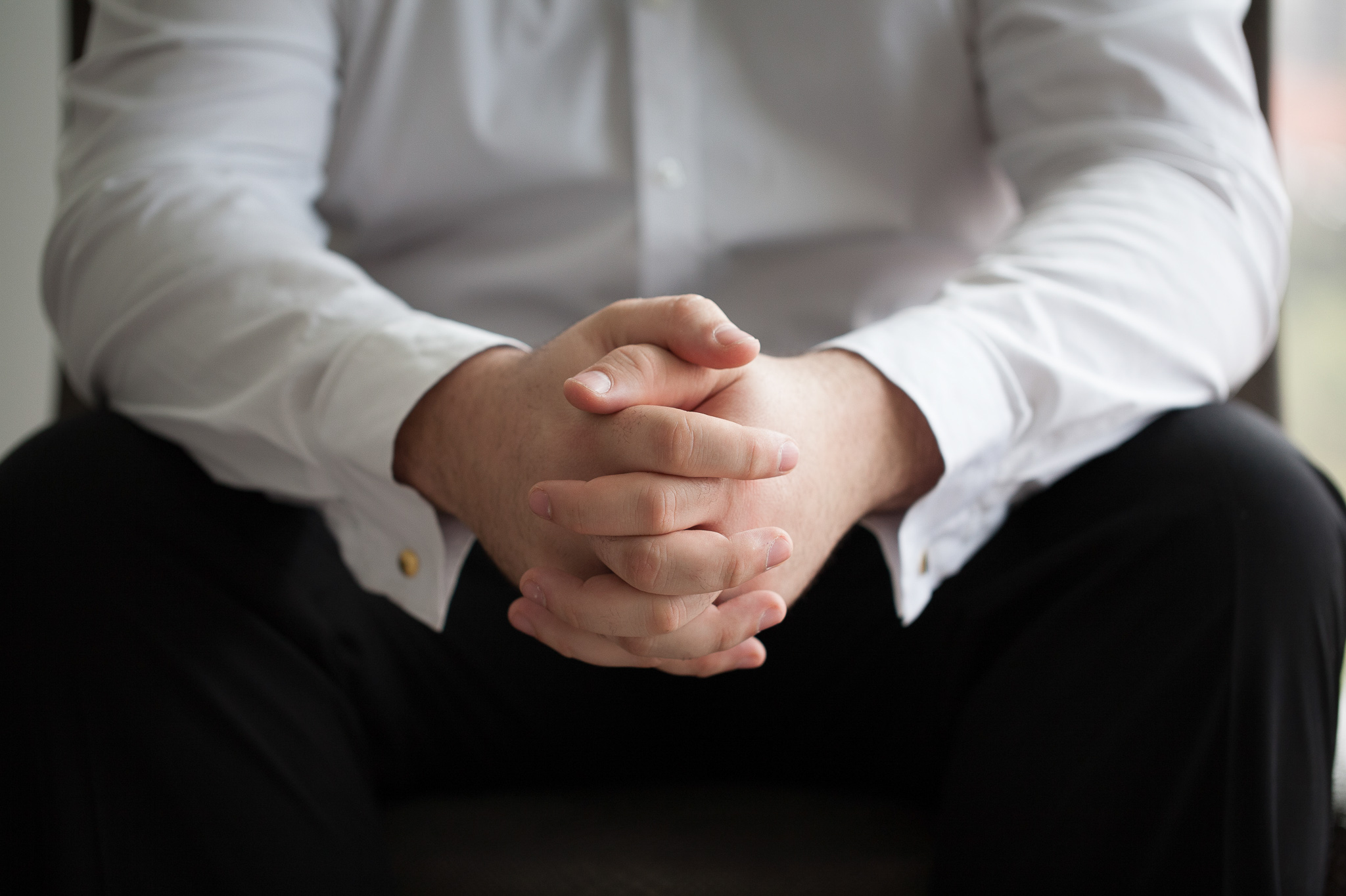 closeup of grooms clasped hands in his lap